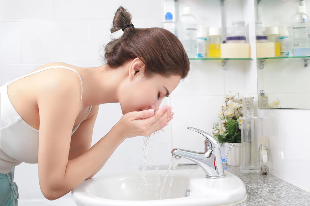 Woman,Washing,Her,Face,With,Water,Above,Bathroom,Sink.