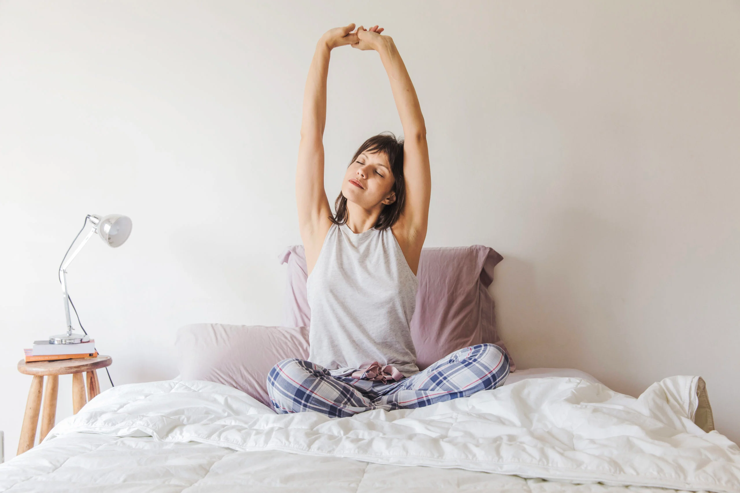 woman-stretching-arms-bed-morning-scaled