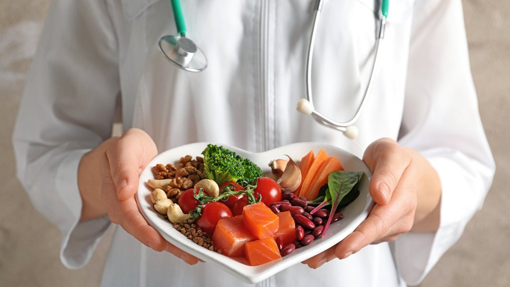 Doctor holding plate with products for heart-healthy diet, close