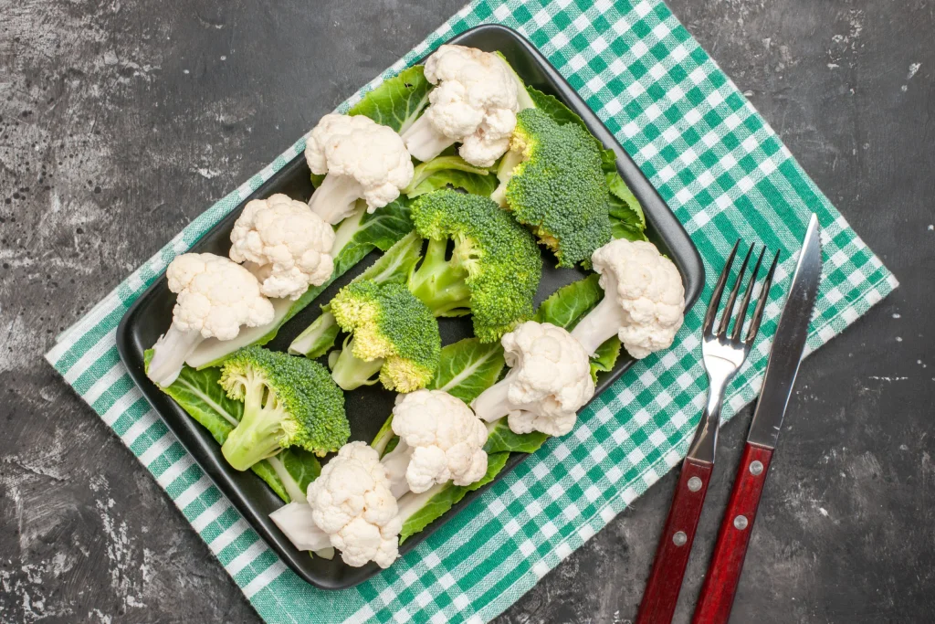 top-view-broccoli-cauliflower-black-rectangular-plate-green-white-checkered-napkin-fork-knife-dark-background-scaled