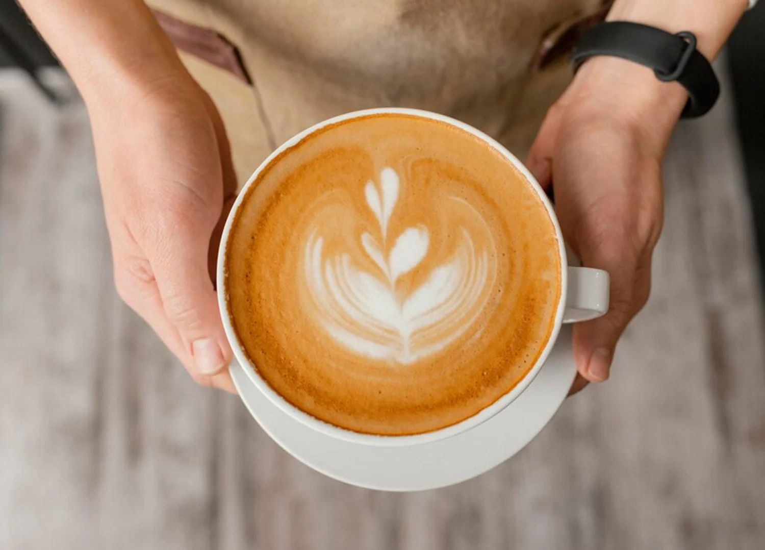 top-view-female-barista-holding-decorated-cup-coffee-hands