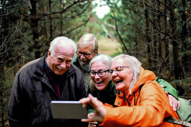 Group,Of,Elderly,Friends,Hiking,In,The,Forest,Using,A