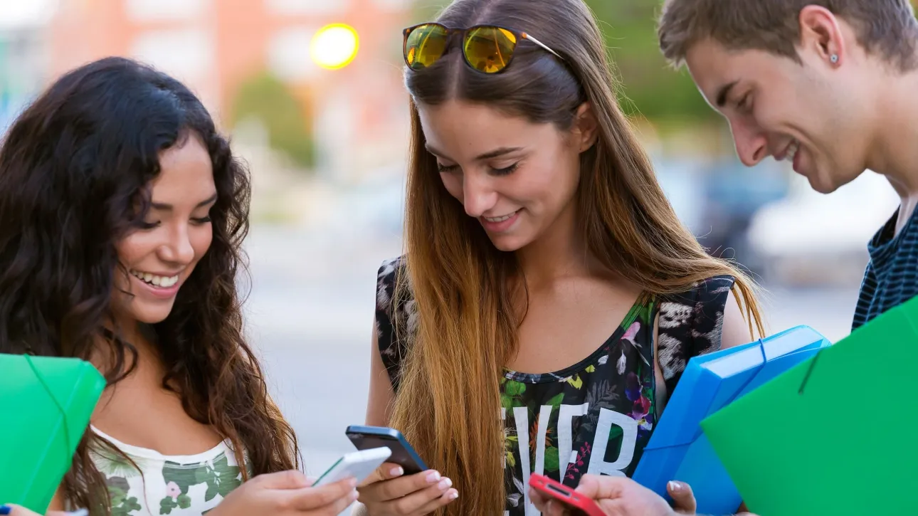 group-students-having-fun-with-smartphones-after-class